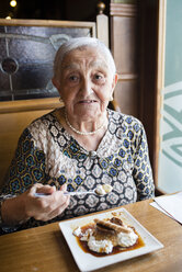 Ältere Frau isst Karamellpudding in einem Restaurant - RAEF000489