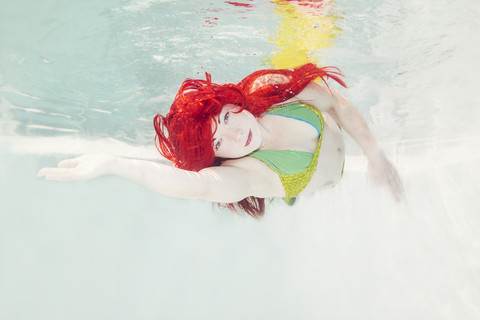 Junge Frau in der Verkleidung von Arielle, der kleinen Meerjungfrau, unter Wasser, lizenzfreies Stockfoto