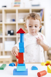 Kleiner Junge baut einen Turm aus blauen und roten Bauklötzen - JRFF000061
