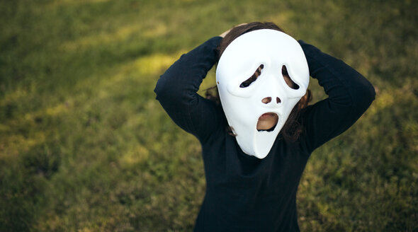 Mädchenmaskerade mit einer Maske auf einer Wiese stehend - MGOF000663