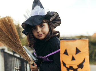 Porträt eines als Hexe verkleideten kleinen Mädchens mit Halloween-Laterne und Besen - MGOF000672