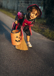 Porträt eines als Hexe verkleideten kleinen Mädchens mit Halloween-Laterne und Besen - MGOF000674