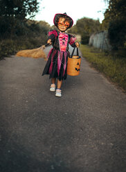 Little girl masquerade as a witch with halloween lantern and broom - MGOF000676