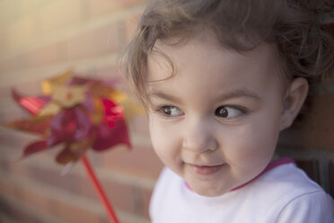 Porträt eines lächelnden kleinen Mädchens mit Windrädchen, das etwas beobachtet - ERLF000032