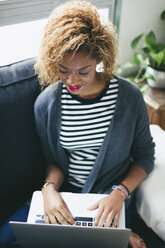 Young woman sitting on the couch using laptop - EBSF000880