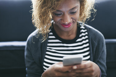 Smiling young woman looking at her smartphone - EBSF000891