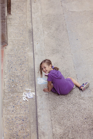 Lächelndes Mädchen zeichnet mit Buntstift auf der Straße, lizenzfreies Stockfoto