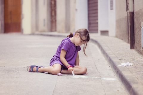 Kleines Mädchen zeichnet mit Buntstift auf der Straße, lizenzfreies Stockfoto