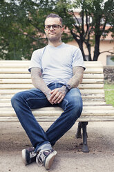 Tätowierter Mann sitzt auf einer Parkbank - XCF000017