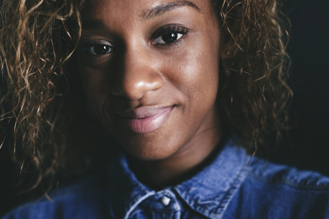 Porträt einer lächelnden jungen Frau vor einem schwarzen Hintergrund, lizenzfreies Stockfoto
