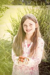 Portrait of smiling girl with handful of strawberries - JUNF000430