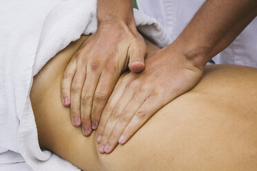 Die Hände eines Physiotherapeuten massieren den Rücken einer Frau - ABZF000120