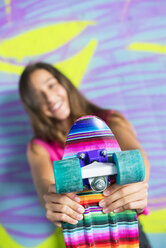 Teenager-Mädchen hält ein buntes Skateboard - GEMF000360