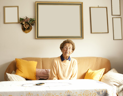 Porträt einer älteren Frau auf der Couch in ihrem Wohnzimmer, lizenzfreies Stockfoto