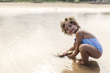 Portrait of smiling little girl wearing swim suit playing at seafront - MGOF000707