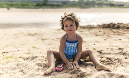 Portrait of smiling little girl wearing swim suit playing on the beach - MGOF000708