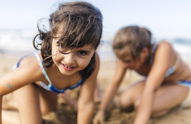 Portrait of smiling little girl playing on the beach - MGOF000718