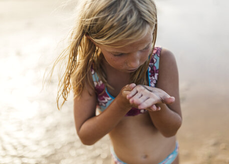 Kleines Mädchen am Strand mit einem Aal auf der Hand - MGOF000721