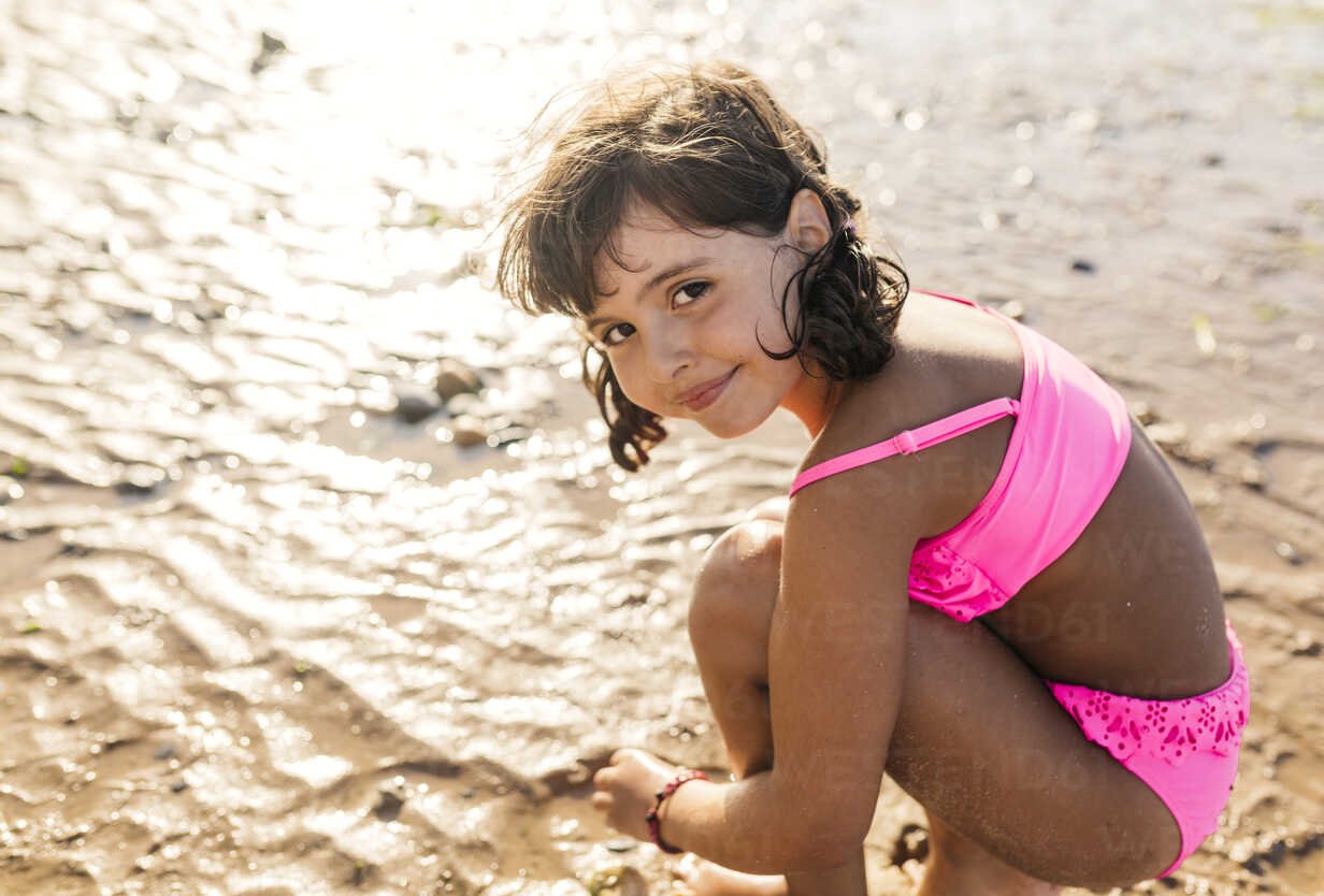 Portrait of smiling little girl wearing pink bikini on the beach stock photo
