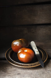 Schwarze Tomaten, Ebeno, Küchenmesser auf Teller - EVGF002272