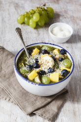 Bowl of green smoothie and fruits sprinkled with coconut flakes - EVGF002256