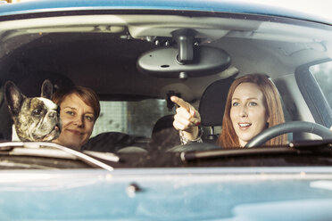 Two female friends sitting in a car with their French bulldog - TAM000308