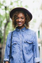 Portrait of smiling young woman wearing hat and denim shirt - EBSF000932