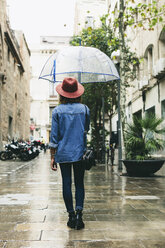 Spain, Barcelona, young woman with umbrella wearing hat and denim shirt - EBSF000926