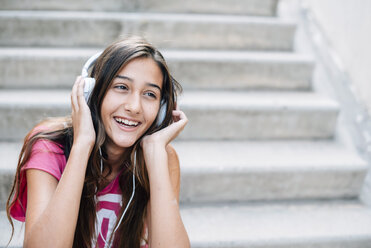 Portrait of smiling teenage girl listening music with headphones - GEMF000381