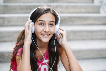 Portrait of smiling teenage girl listening music with headphones - GEMF000385