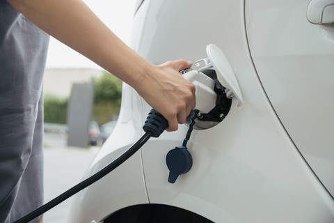 Young woman charging electric car stock photo