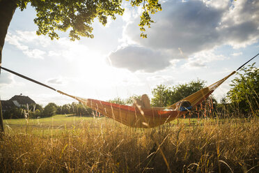 Woman with headphones lying in a hammock relaxing in nature - UUF005636