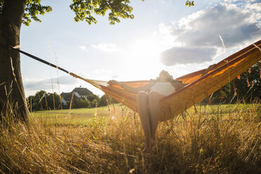 Woman with headphones lying in a hammock relaxing in nature - UUF005638