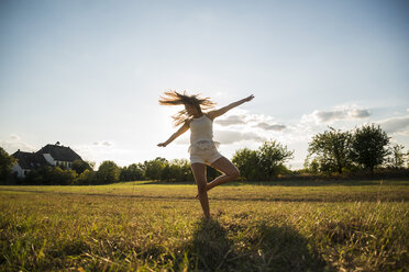 Young woman dancing on a meadow at backlight - UUF005641
