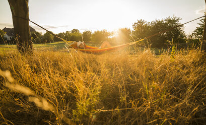 Woman relaxing in a hammock at backlight - UUF005659