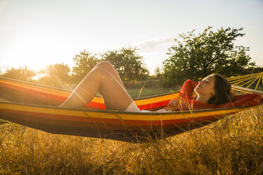 Woman relaxing in a hammock at backlight - UUF005664