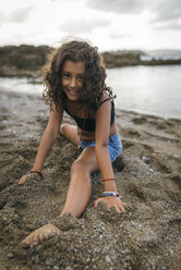 Spain, Gijon, portrait of smiling little girl doing the splits on a beach - MGOF000735