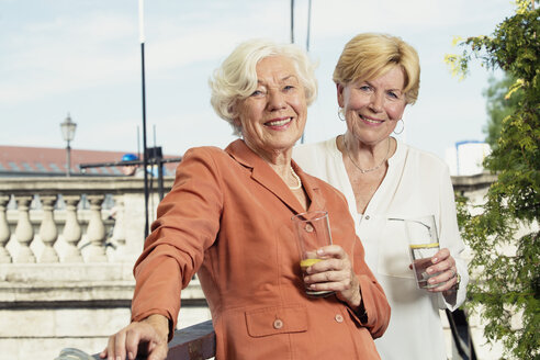 Deutschland, Berlin, Porträt von zwei lächelnden Seniorinnen mit Mineralwassergläsern - TAMF000330
