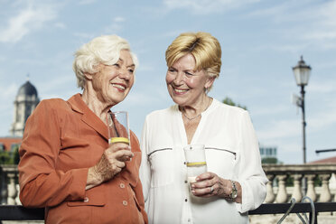 Deutschland, Berlin, Porträt von zwei lächelnden Seniorinnen mit Mineralwassergläsern - TAMF000333