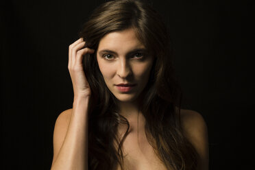 Portrait of brunette young woman in front of black background - SHKF000366