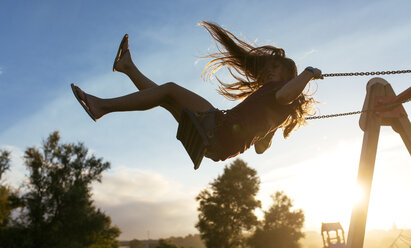 Girl with blowing hair on a swing at backlight - MGOF000752