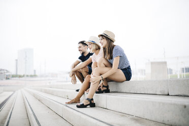 Spanien, Barcelona, drei lachende Freunde sitzen nebeneinander auf einer Treppe - JRFF000070