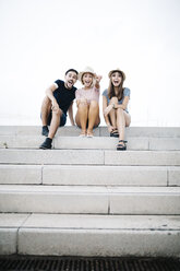 Drei aufgeregte Freunde sitzen Seite an Seite auf einer Treppe - JRFF000071