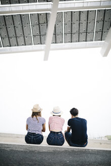 Rückenansicht von drei Freunden, die nebeneinander auf einer Stufe sitzen - JRFF000073