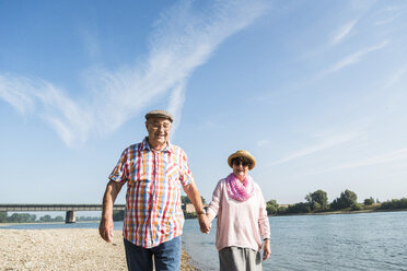 Deutschland, Ludwigshafen, glückliches älteres Paar, das Hand in Hand am Flussufer spazieren geht - UUF005670