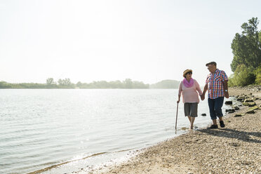 Deutschland, Ludwigshafen, älteres Paar geht Hand in Hand am Flussufer spazieren - UUF005708