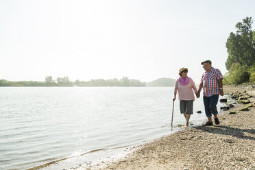 Germany, Ludwigshafen, senior couple walking hand in hand at riverside - UUF005708