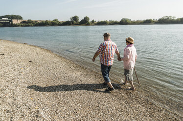 Germany, Ludwigshafen, senior couple walking hand in hand at riverside - UUF005673