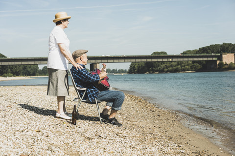 Deutschland, Ludwigshafen, Seniorenpaar entspannt sich am Flussufer, lizenzfreies Stockfoto