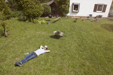 Mann liegt auf dem Rasen und entspannt sich von der Gartenarbeit - RBF003202